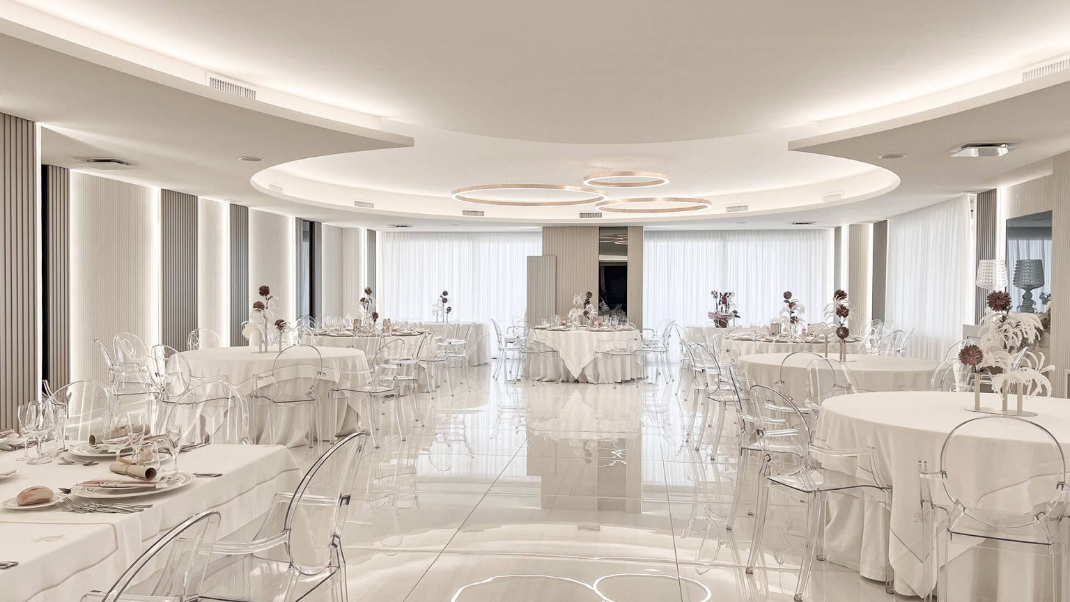 Sala Preziosa: ambiente bianco e avorio con tavoli rotondi e grandi vetrate